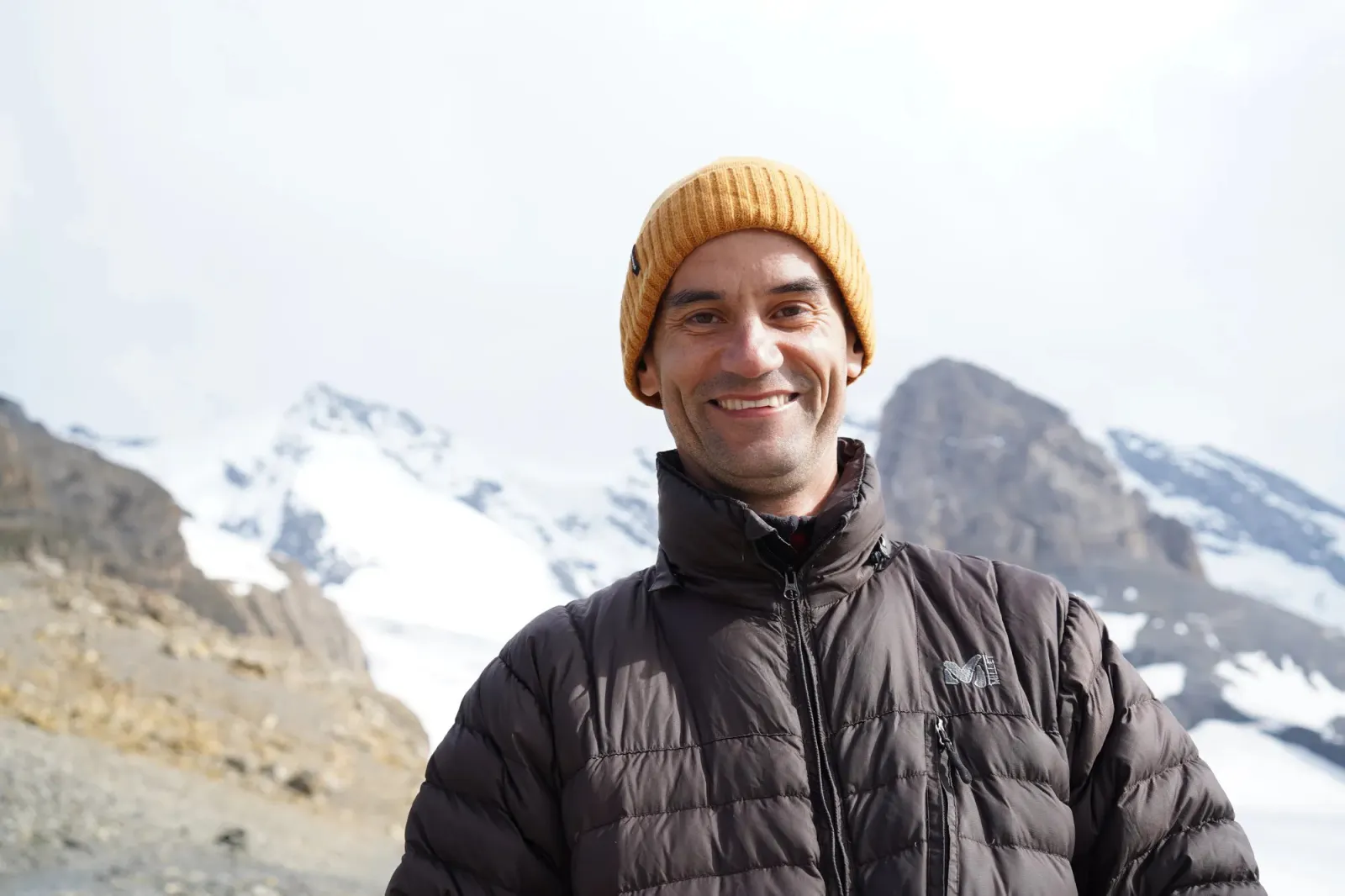 Holger Yeshe lachend vor verschneiten Bergen
