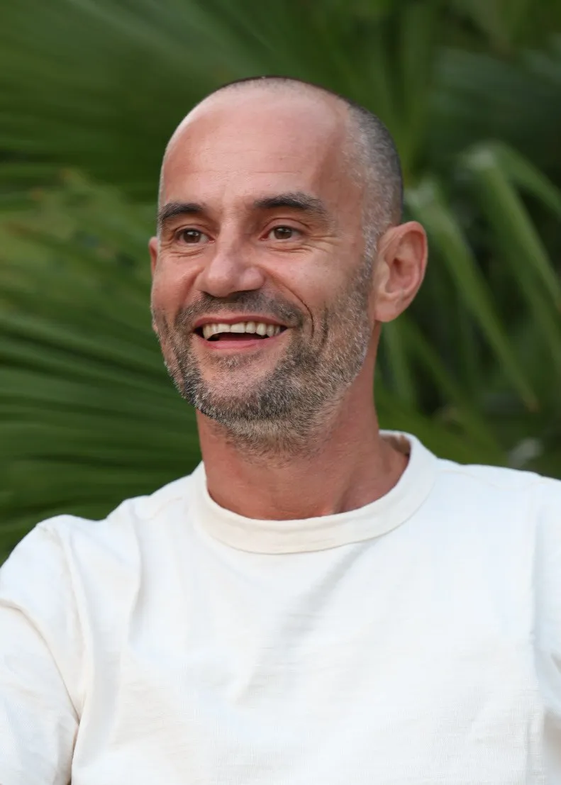 Holger Yeshe lachend vor grünen Palmblättern